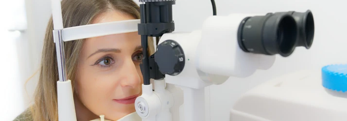 Eye Doctor Newberg OR Services A patient sitting forward with her chin resting on the base of exam machinery during an exam